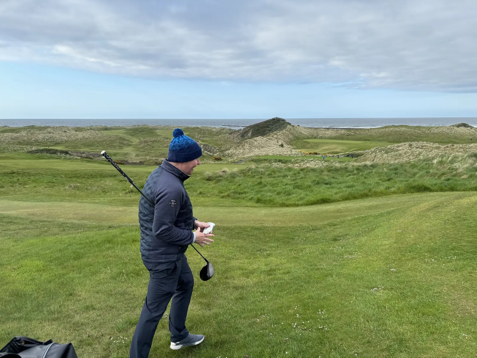 Golfer in a woolly hat and insulated jacket among the dunes at Castlerock Golf Club on the Causeway Coast in May